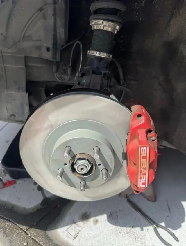 New front rotor installed on a Subaru in the customer's driveway